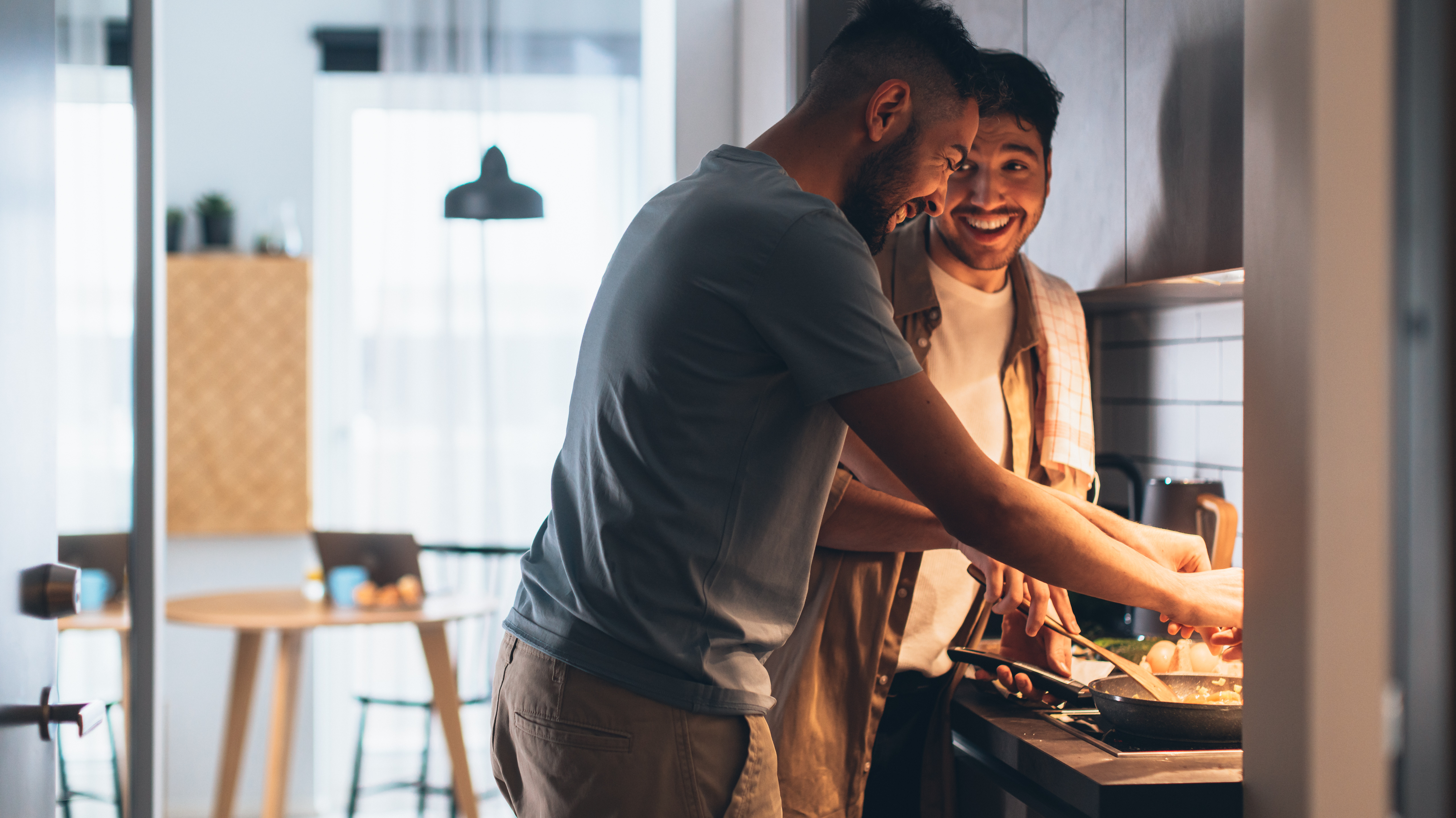 A couple cooking together in a kitchen.